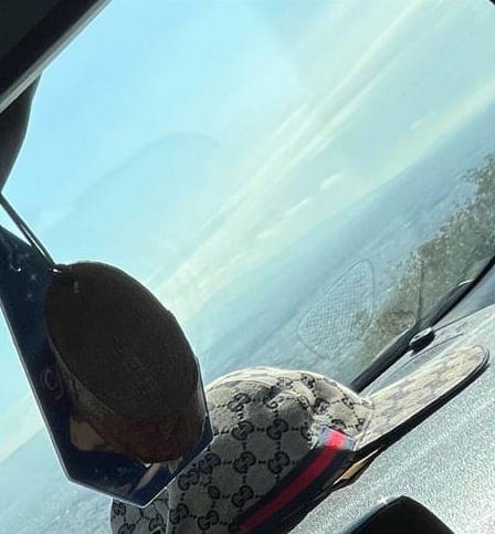 Καπέλο Gucci σε ταμπλό αυτοκινήτου, με θάλασσα και ουρανό στο βάθος