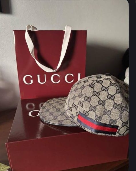 Καπέλο Gucci μπροστά από κόκκινη τσάντα και κουτί Gucci