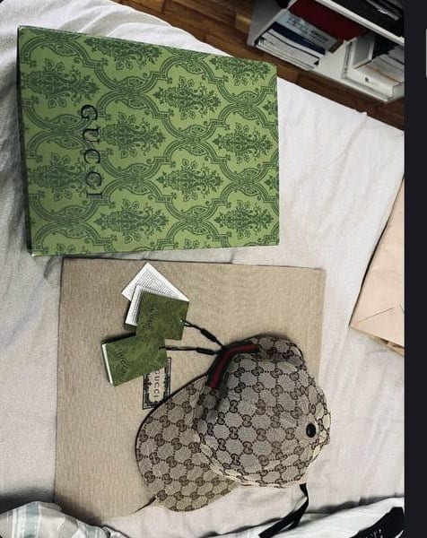 Πράσινο κουτί Gucci και καπέλο με μονόγραμμα, σε λευκό σεντόνι